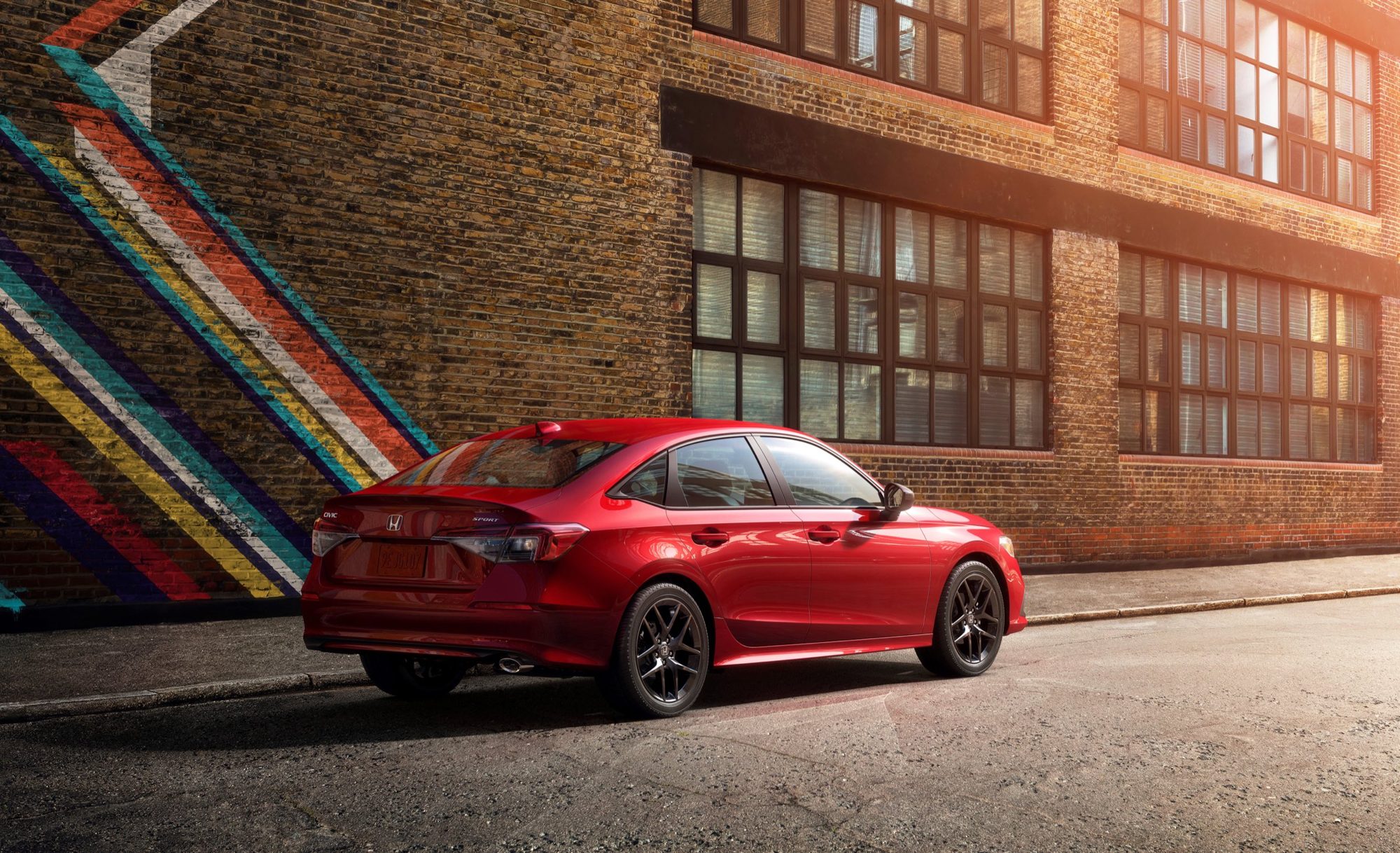 2022 Honda Civic Review: Best got better at age 50 6 Rear three-quarter view of a red 2022 Honda Civic Sport sedan parked by a brick building