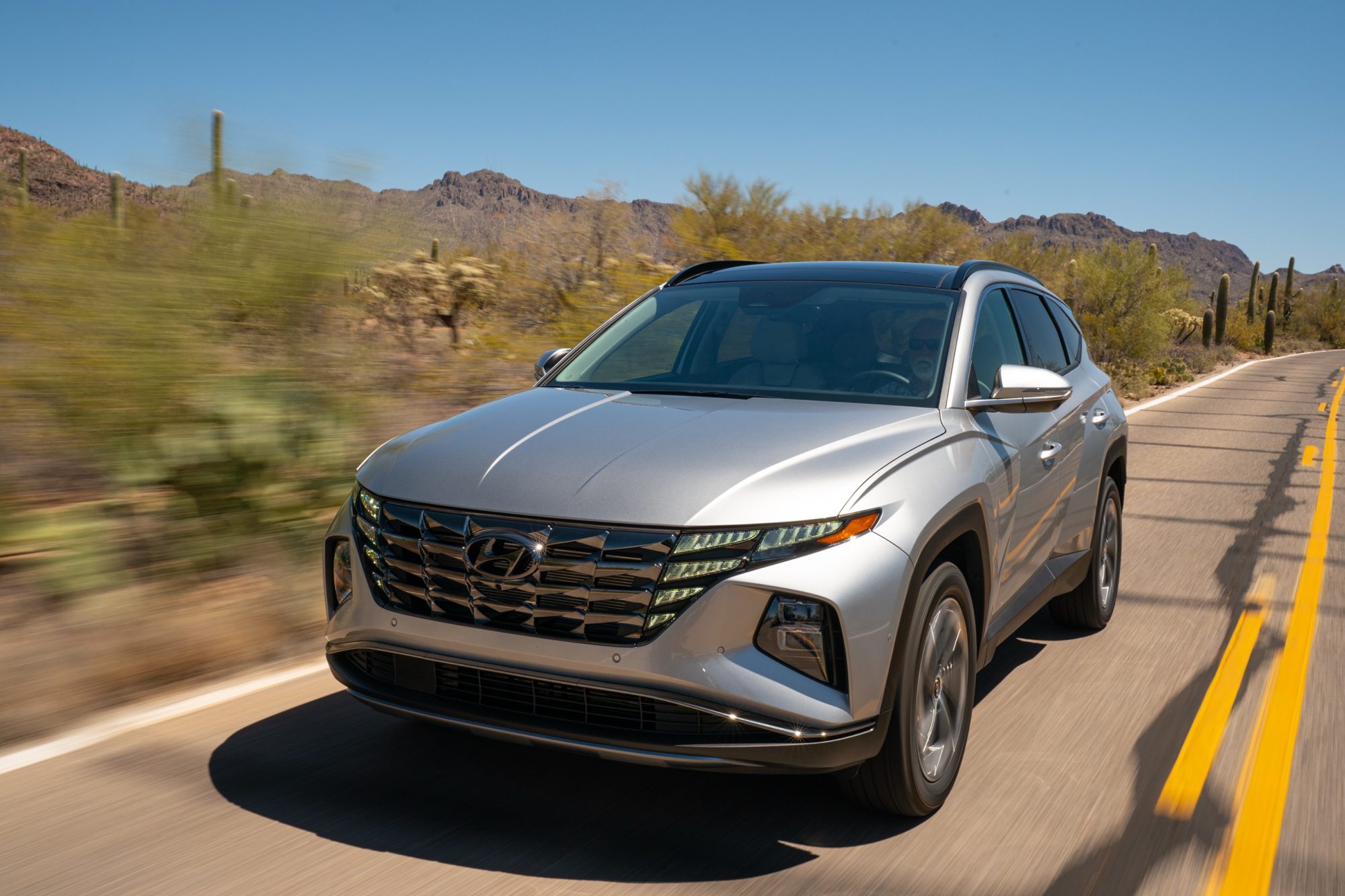 Silver 2022 Hyundai Tucson Hybrid driving on a desert highway