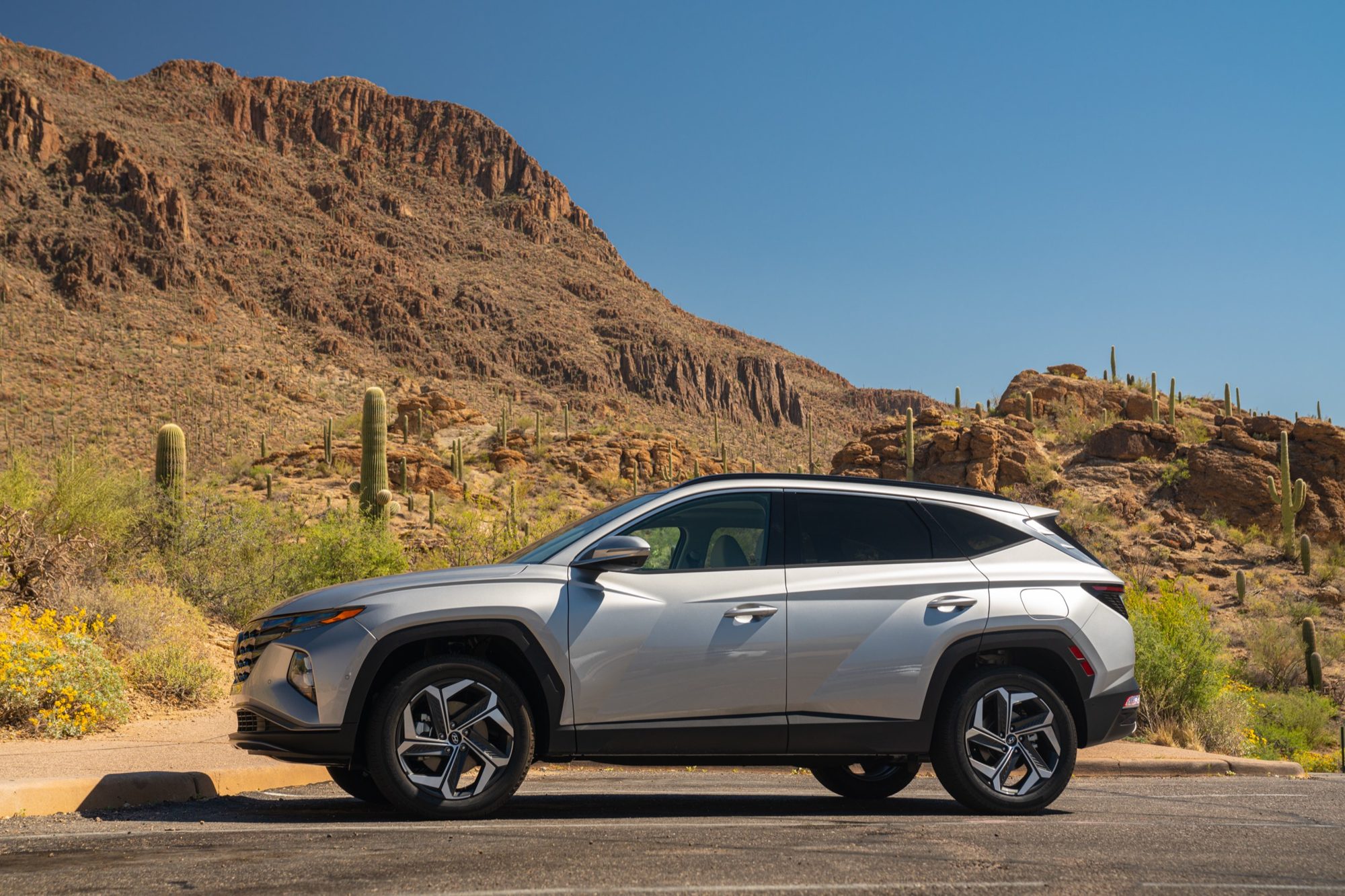 Side profile of a silver 2022 Hyundai Tucson Hybrid in the Arizona desert