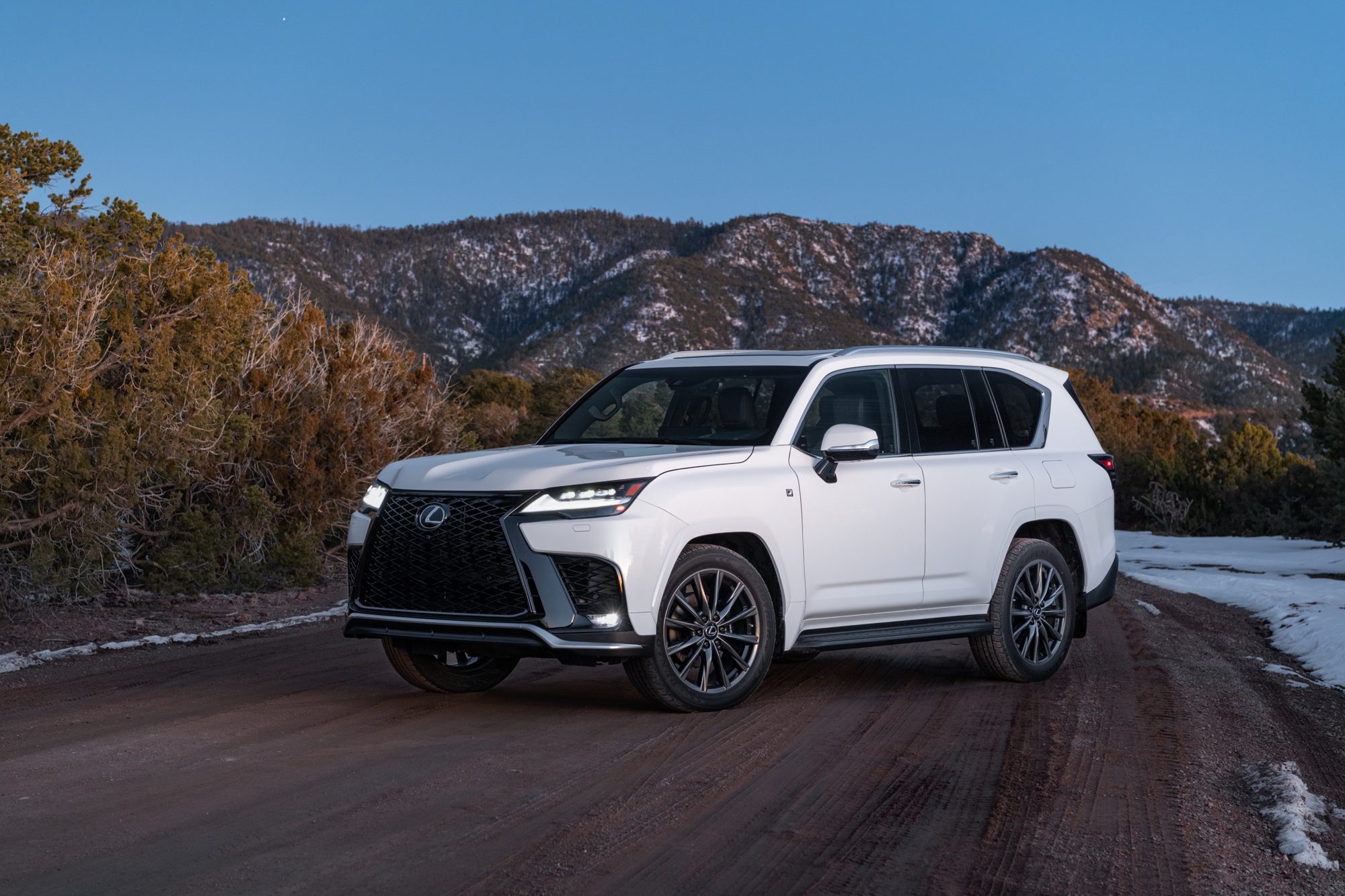 Front three-quarter view of a white 2022 Lexus LX 600 F Sport Handling on a mountain road