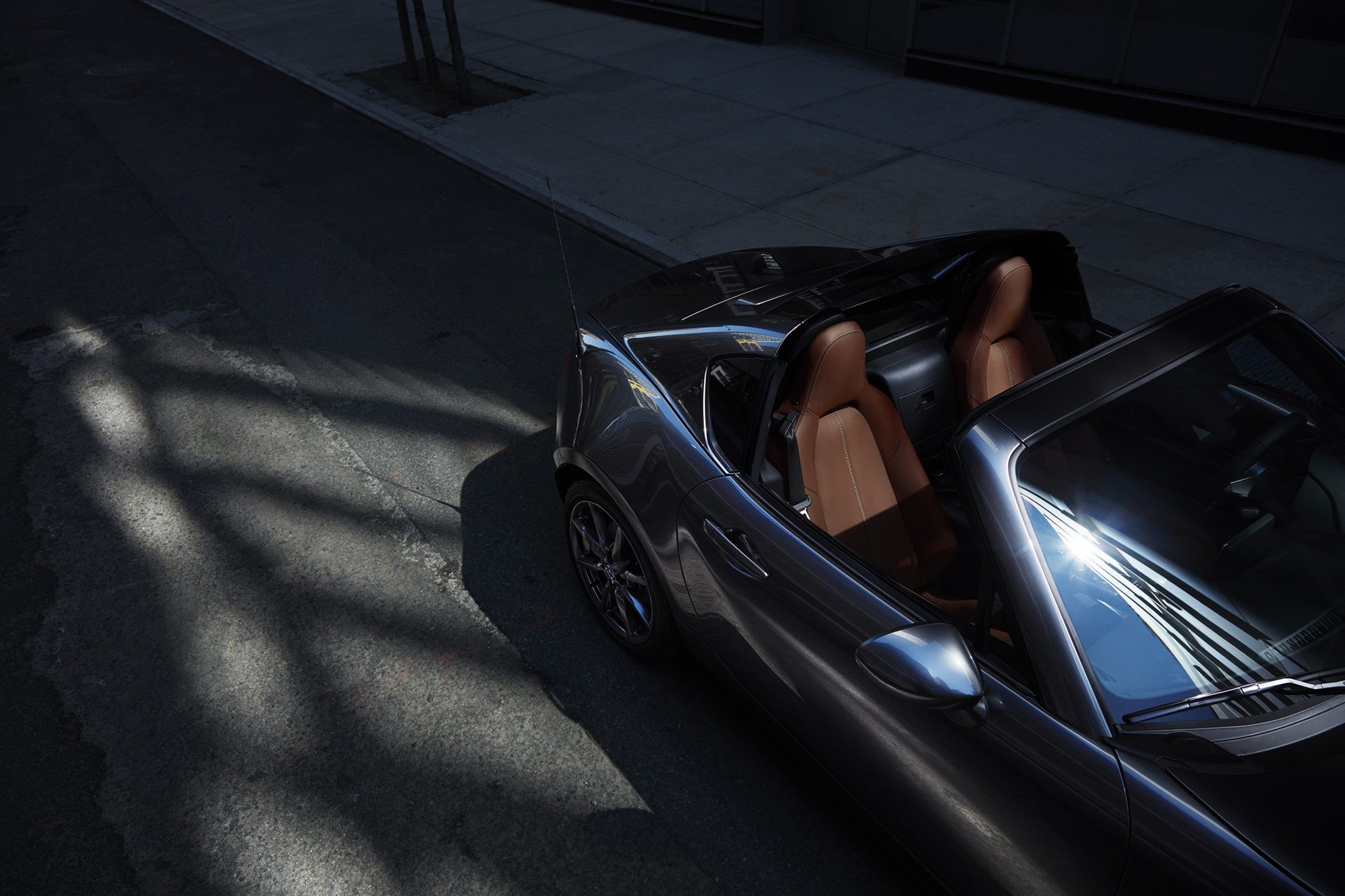 Overhead view of a gray 2022 Mazda MX-5 Miata RF with its roof panel open and brown leather seats