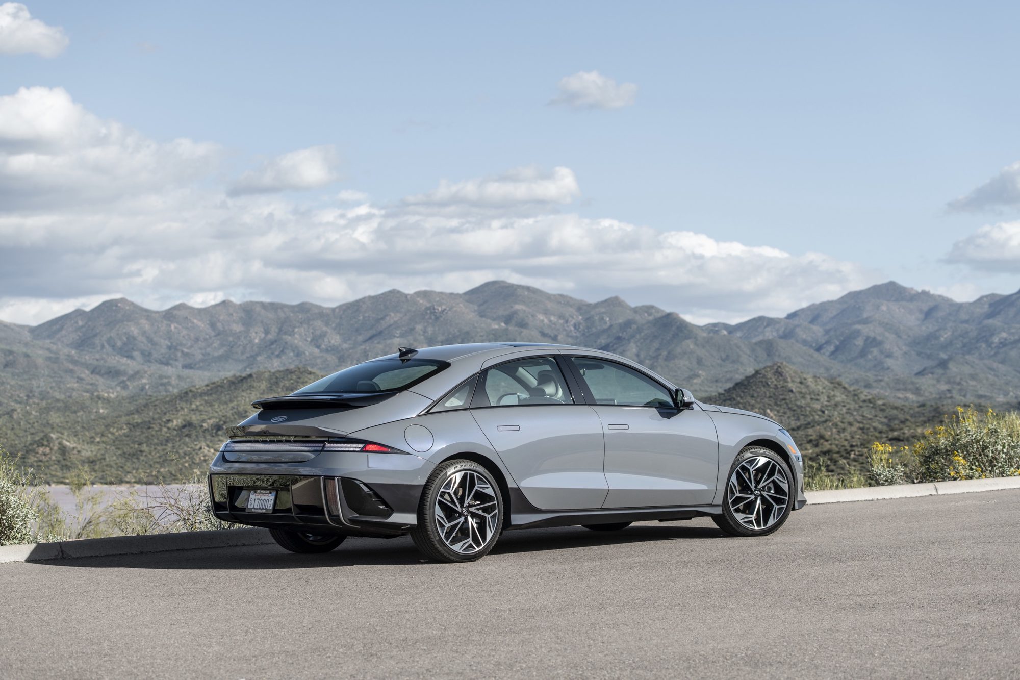 Rear three-quarter view of a gray 2024 Hyundai Ioniq 6 Limited with mountains behind