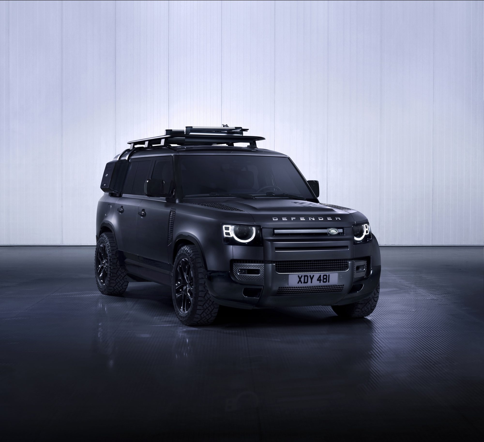 Front three-quarter view of the 2024 Land Rover Defender 130 Outbound in a dark finish with roof rack