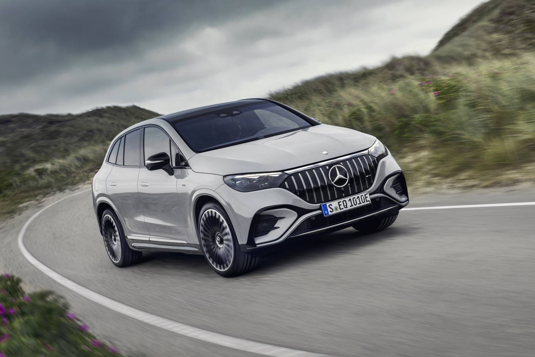 Silver 2024 Mercedes-AMG EQE SUV cornering on a coastal road