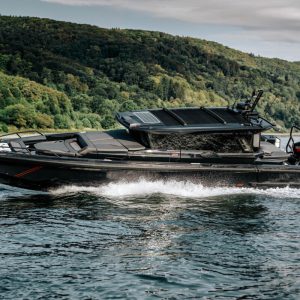 Black Brabus Shadow 1000 XC Cross Cabin powerboat running at speed past a wooded hillside
