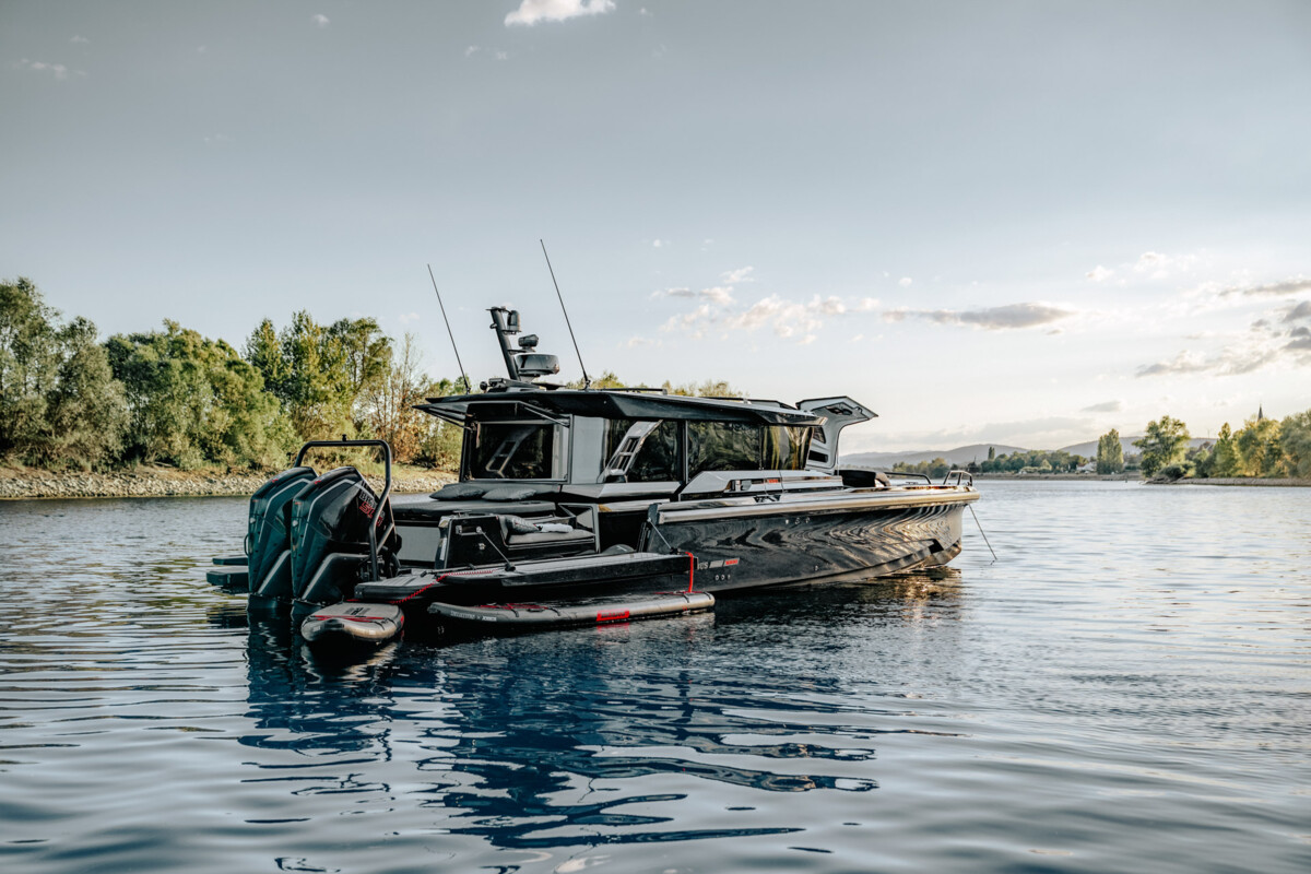 Brabus Shadow 1000 XC Cross Cabin at anchor seen from the stern, showing twin outboard engines and side platforms