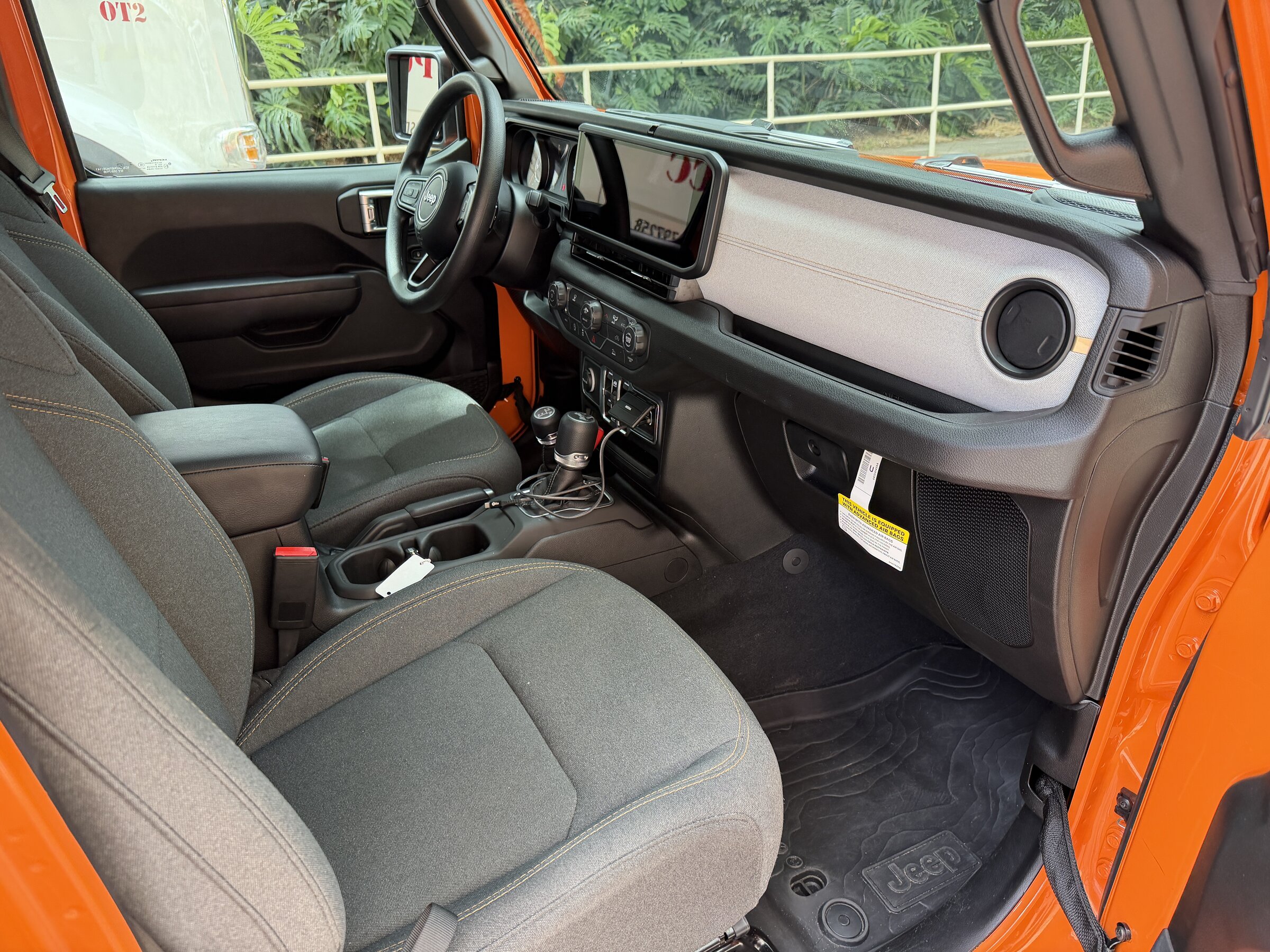 Driving Oahu in a 2026 Jeep Wrangler, From Blue Skies to Hurricane Weather 8 Dashboard of a 2026 Jeep Wrangler Sport with the 12.3-inch Uconnect touchscreen and cloth seats