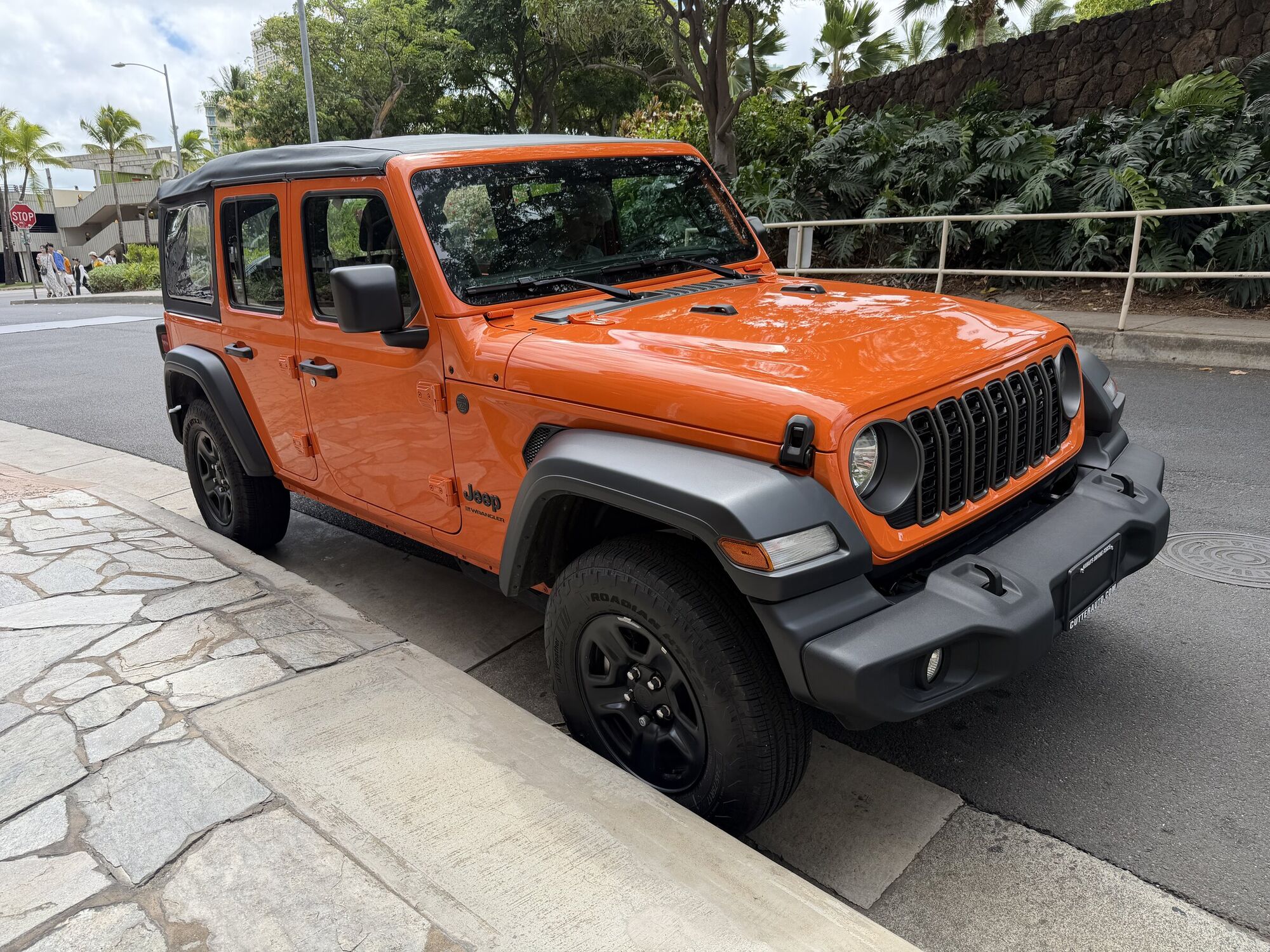 Driving Oahu in a 2026 Jeep Wrangler, From Blue Skies to Hurricane Weather 2 2026 Jeep Wrangler Sport 4-door in Joose orange parked at my hotel for the handoff