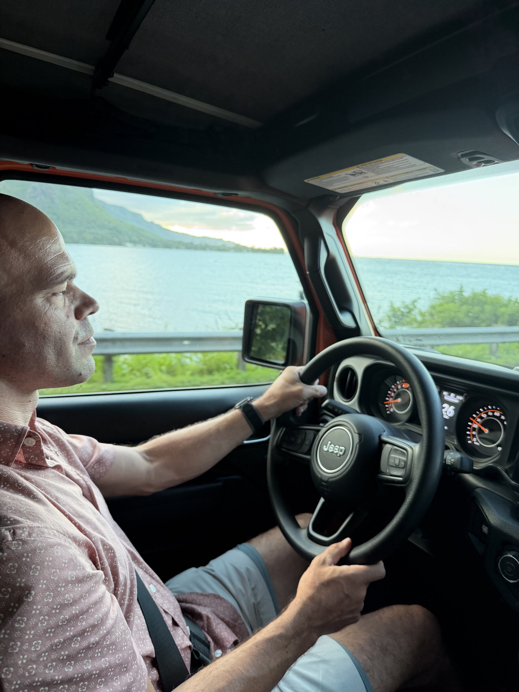 Driving the 2026 Jeep Wrangler Sport along Oahu's windward coast in the evening with the soft top closed