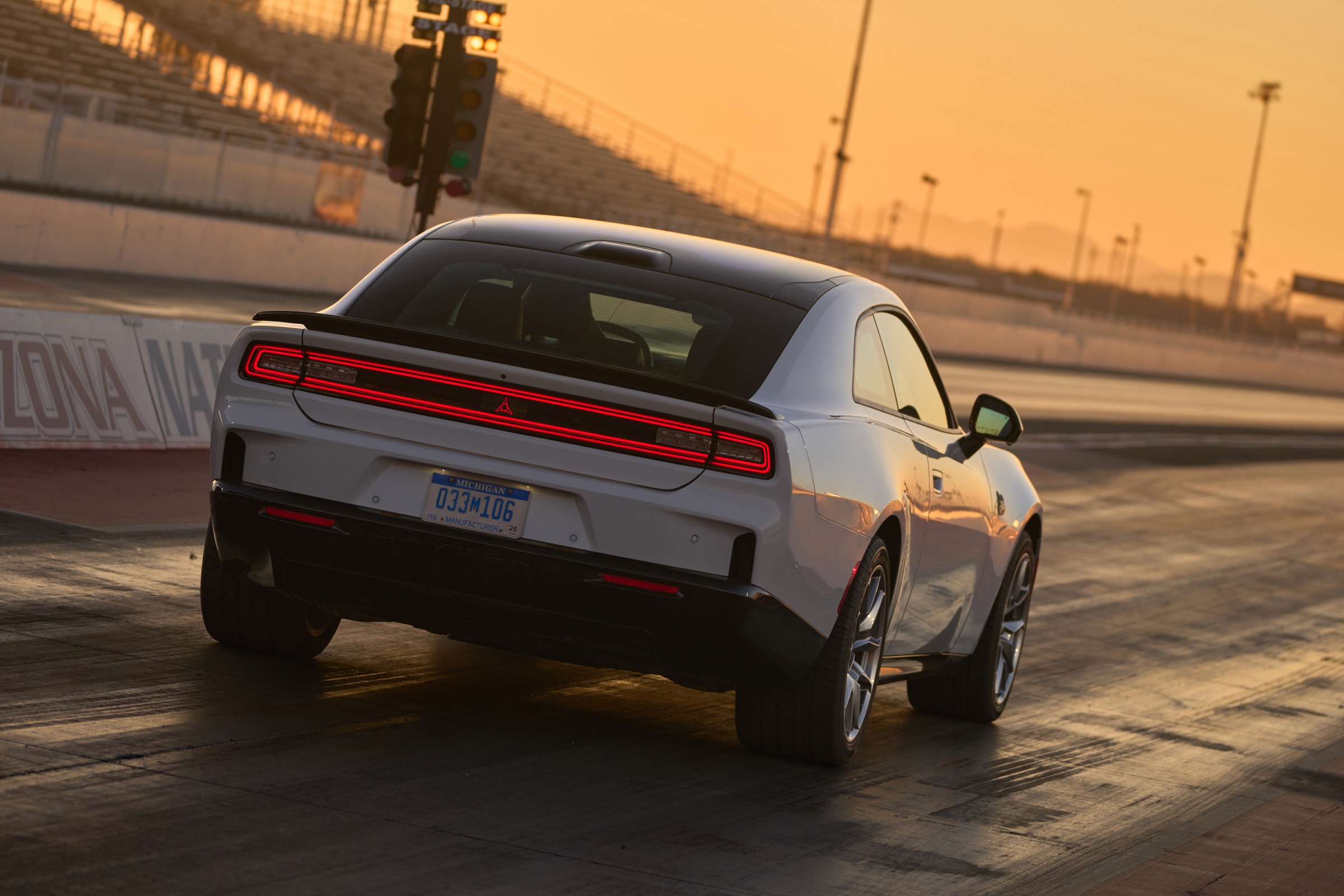 White Dodge Charger Daytona Scat Pack two-door at a drag strip, rear three-quarter view showing the full-width taillamp