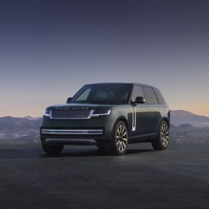 Dark green 2027 Range Rover Electric parked at dusk with mountains behind, front three-quarter view
