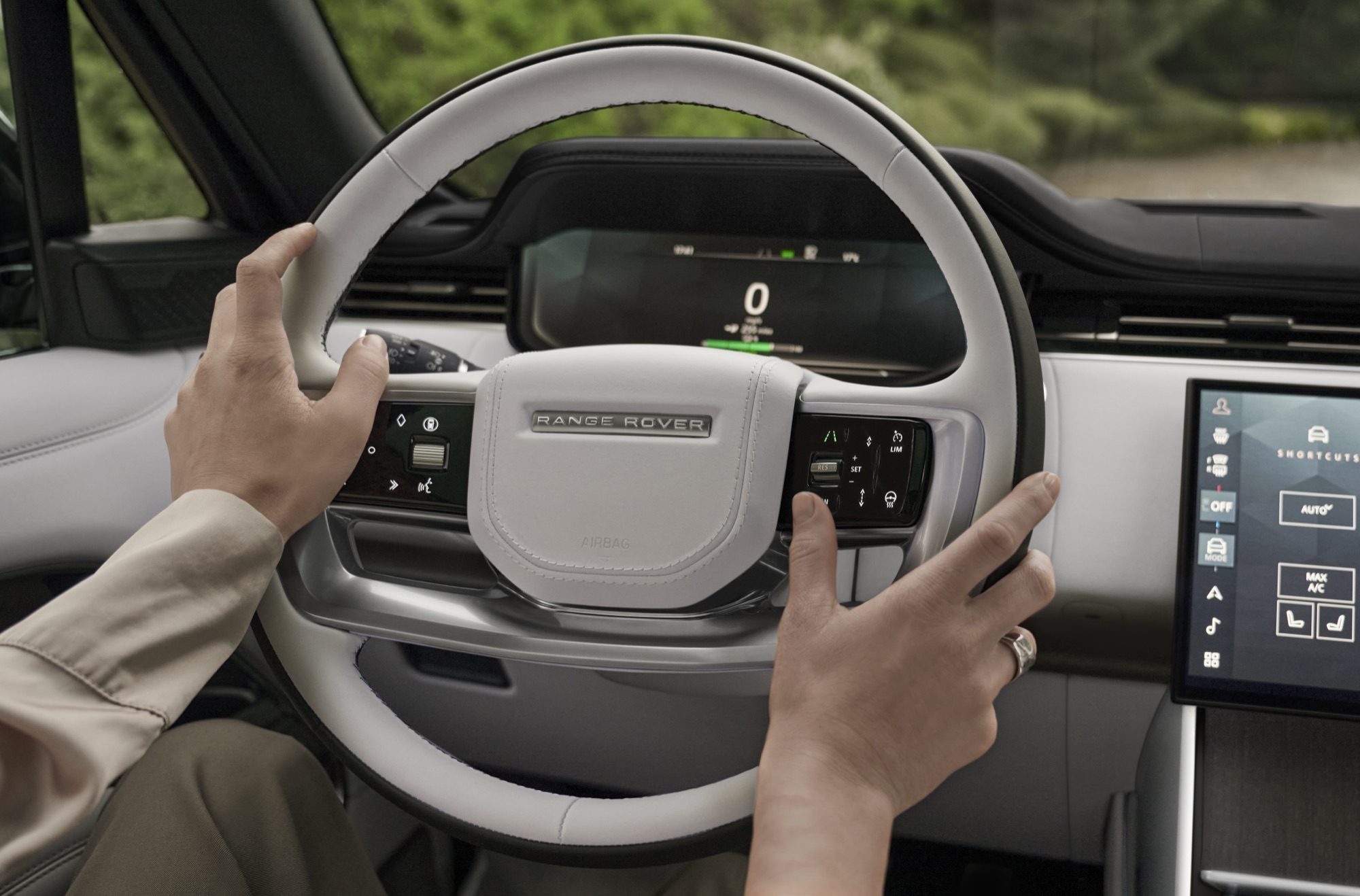 Range Rover Electric Starts at $138,000, the Same Price as the V8 SE 9 Driver's hands on the Range Rover Electric steering wheel with the digital instrument display behind it