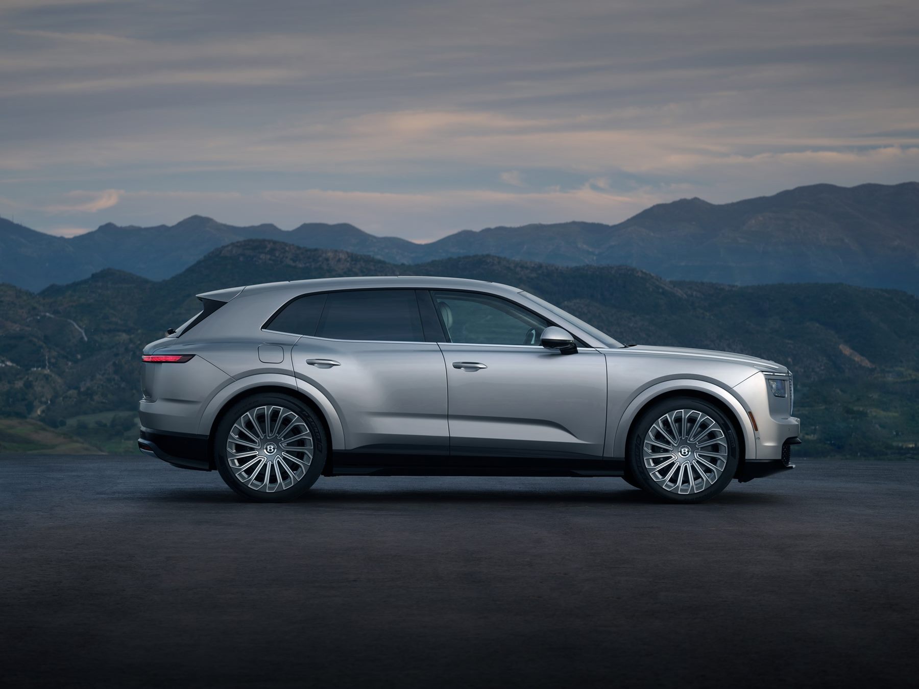 Silver Bentley Torcal in side profile against mountains, showing the long wheelbase and tapering roofline