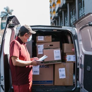 Delivery driver checking paperwork beside an open cargo van on a city street