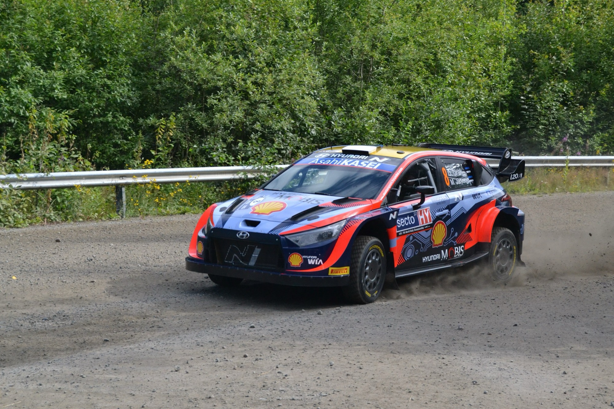 Hyundai i20 N Rally1 number 8 in blue, red and gold livery cornering on gravel at Rally Finland