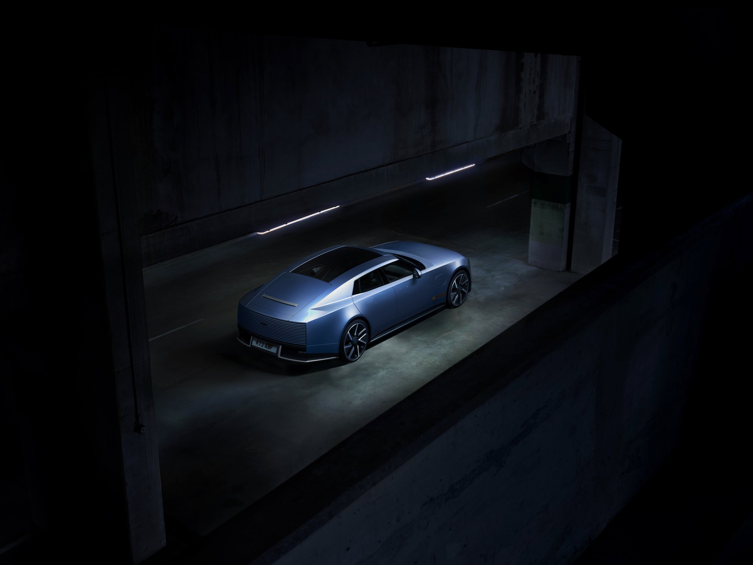 Blue Jaguar Type 01 seen from above and behind in a dark concrete space