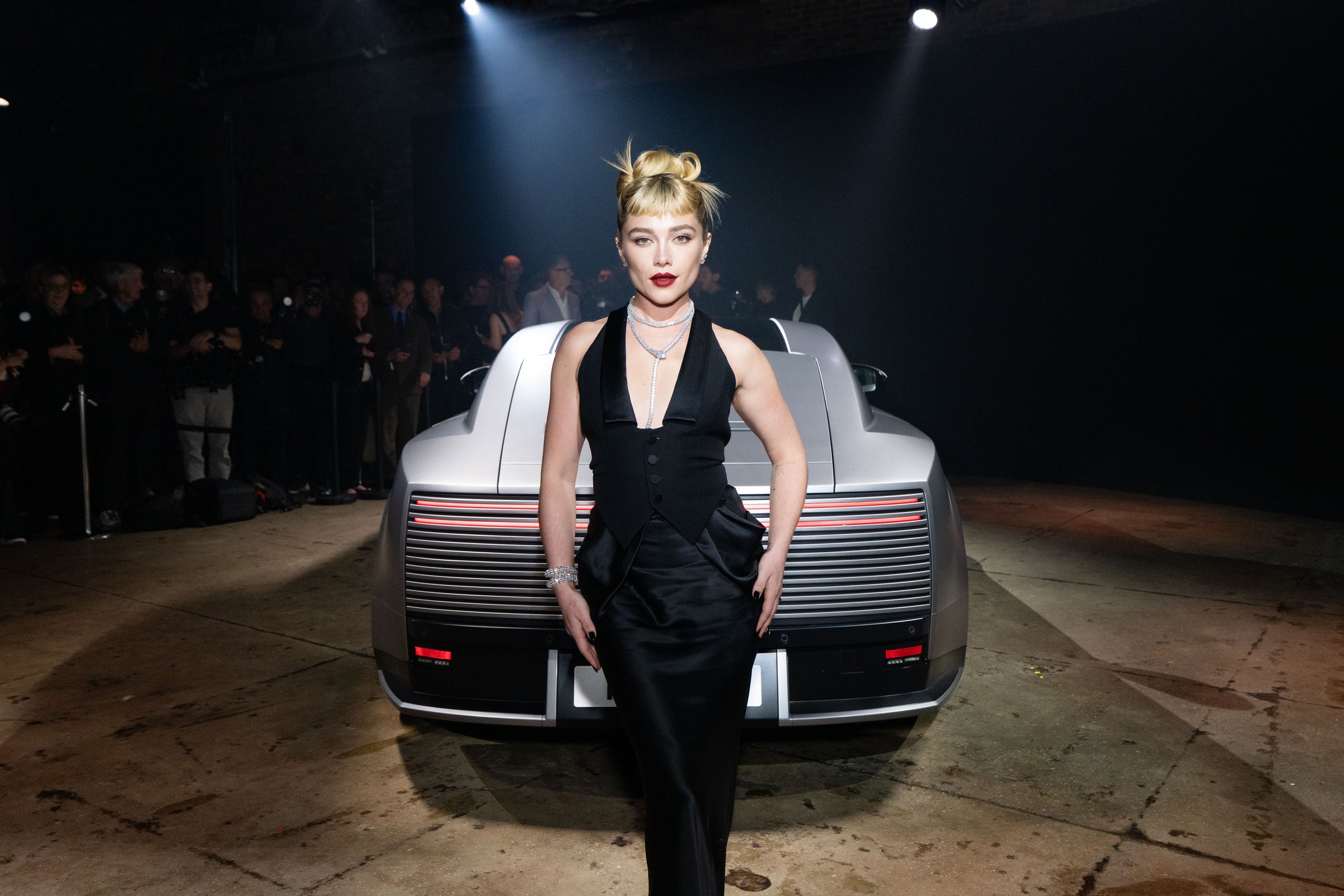 Florence Pugh standing in front of a silver Jaguar Type 01 at its world premiere in New York