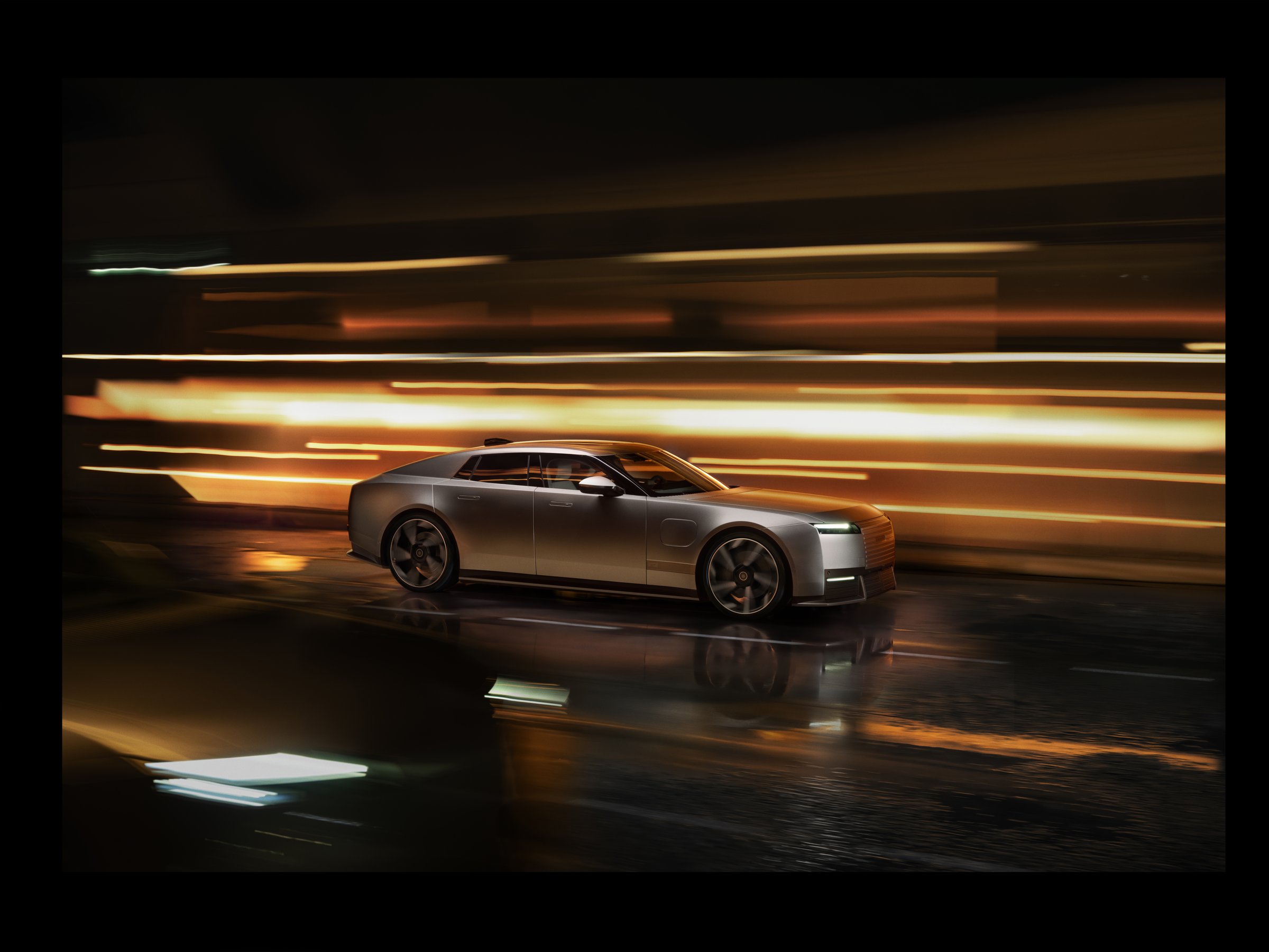 Silver Jaguar Type 01 four-door GT in side profile on a wet street at night with light trails