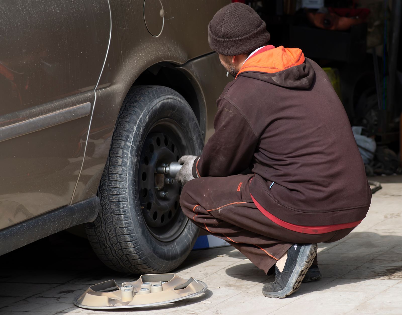 Mechanic changing a car wheel outside a garage
