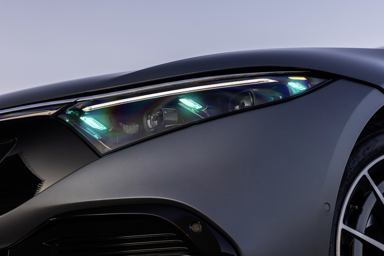Close-up of a Mercedes-Benz EQS headlamp with turquoise automated driving marker lights lit