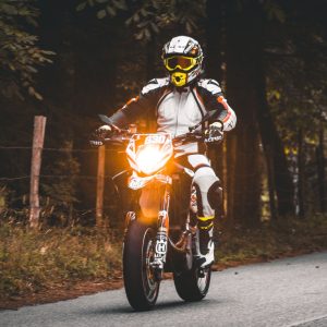 Motorcyclist in full protective gear riding with the headlight on