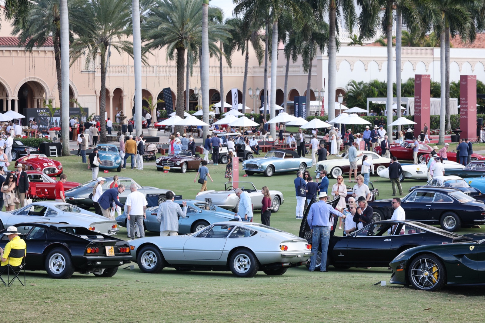 Crowds walk among Ferraris in front of the arcaded pink Cloister building at The Boca Raton during the 2026 Palm Beach Cavallino Classic