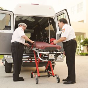 Paramedics loading a stretcher into an ambulance outside a hospital