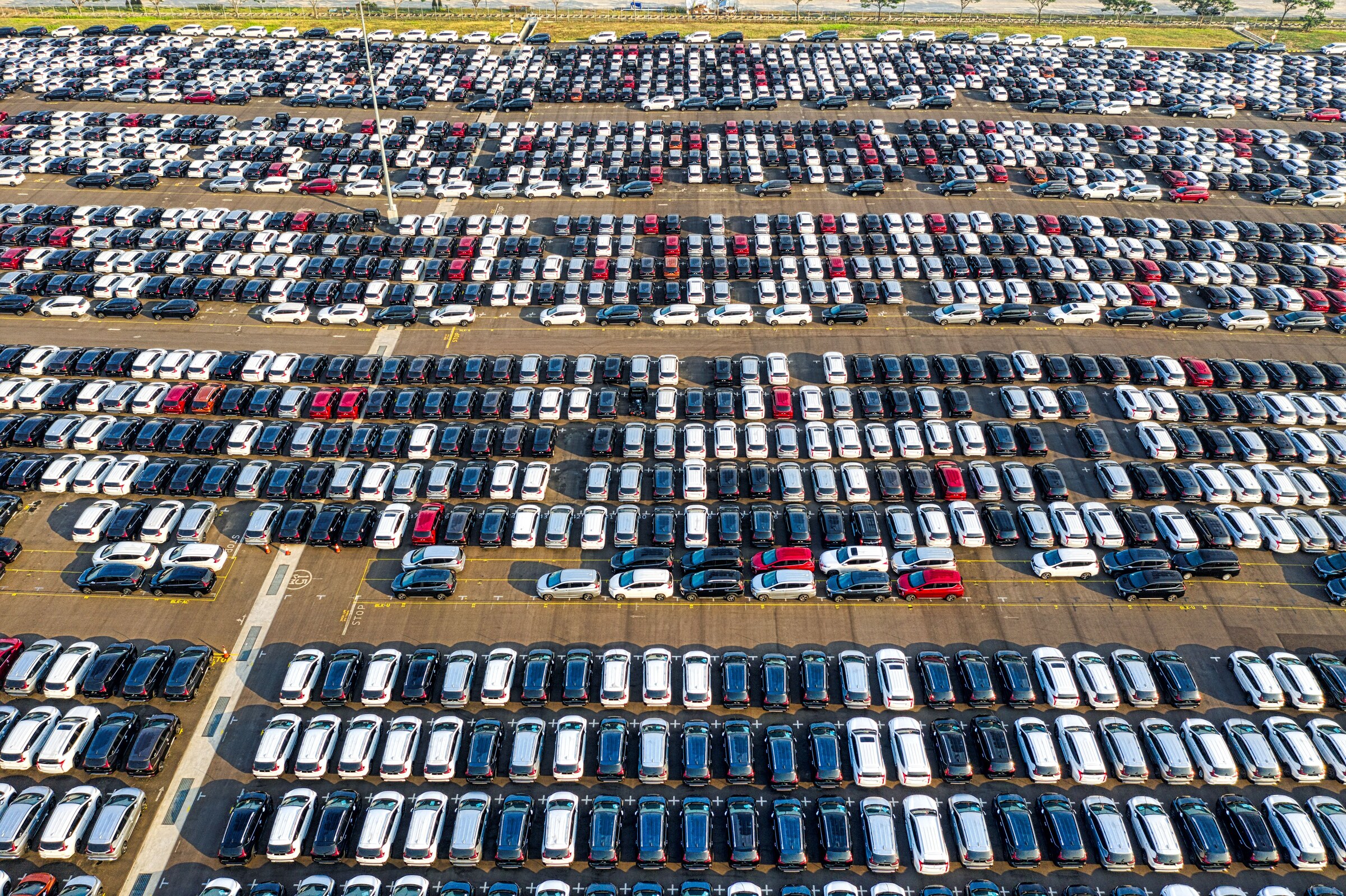 Aerial view of rows of cars parked on a large vehicle lot