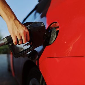 Driver refuelling a red car at a petrol pump