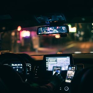 Driver at night with a phone and navigation screen lit on the dashboard