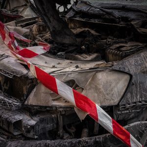 Front end of a wrecked car wrapped in red and white caution tape after a crash