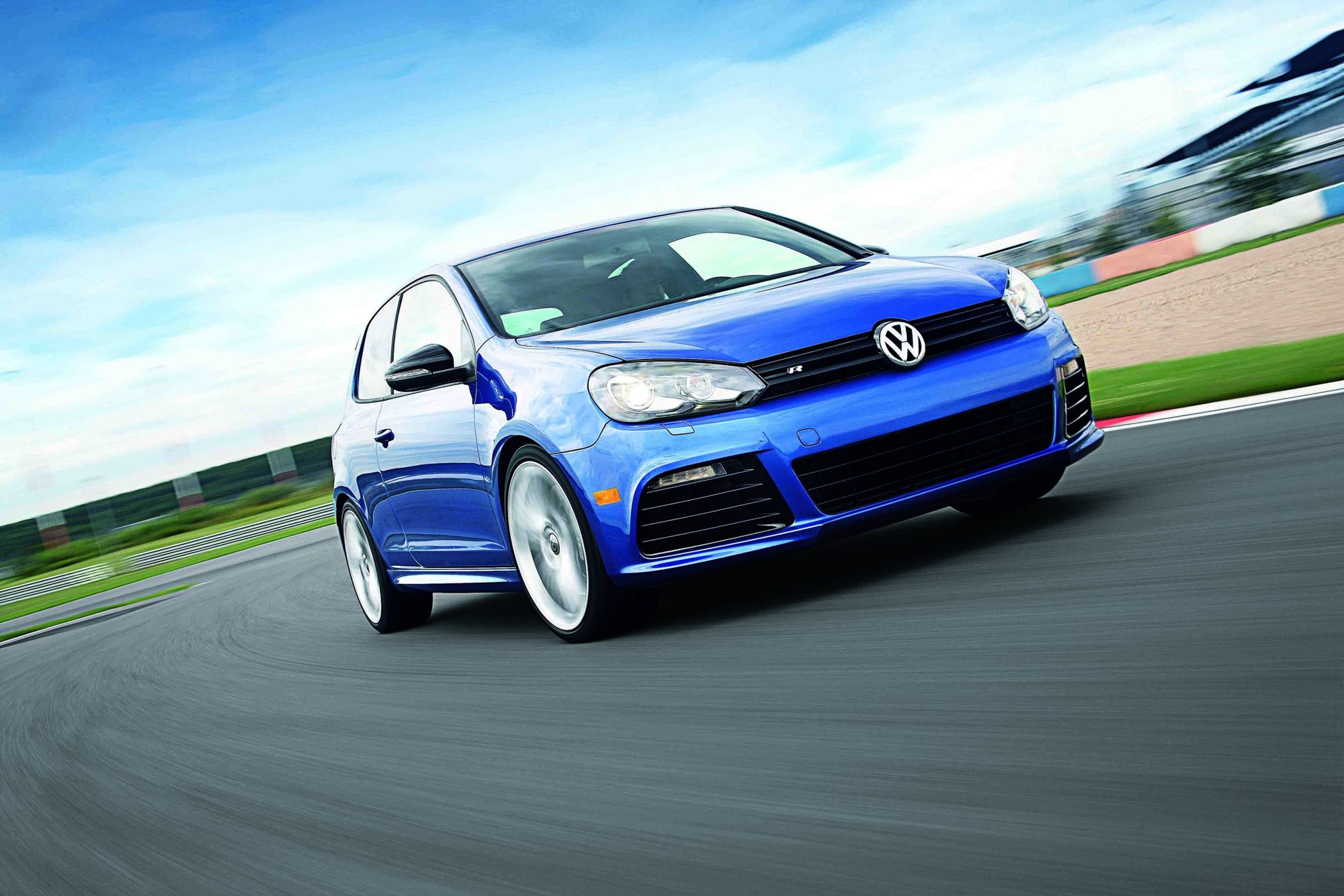 A blue two-door Volkswagen Golf R cornering on a race track