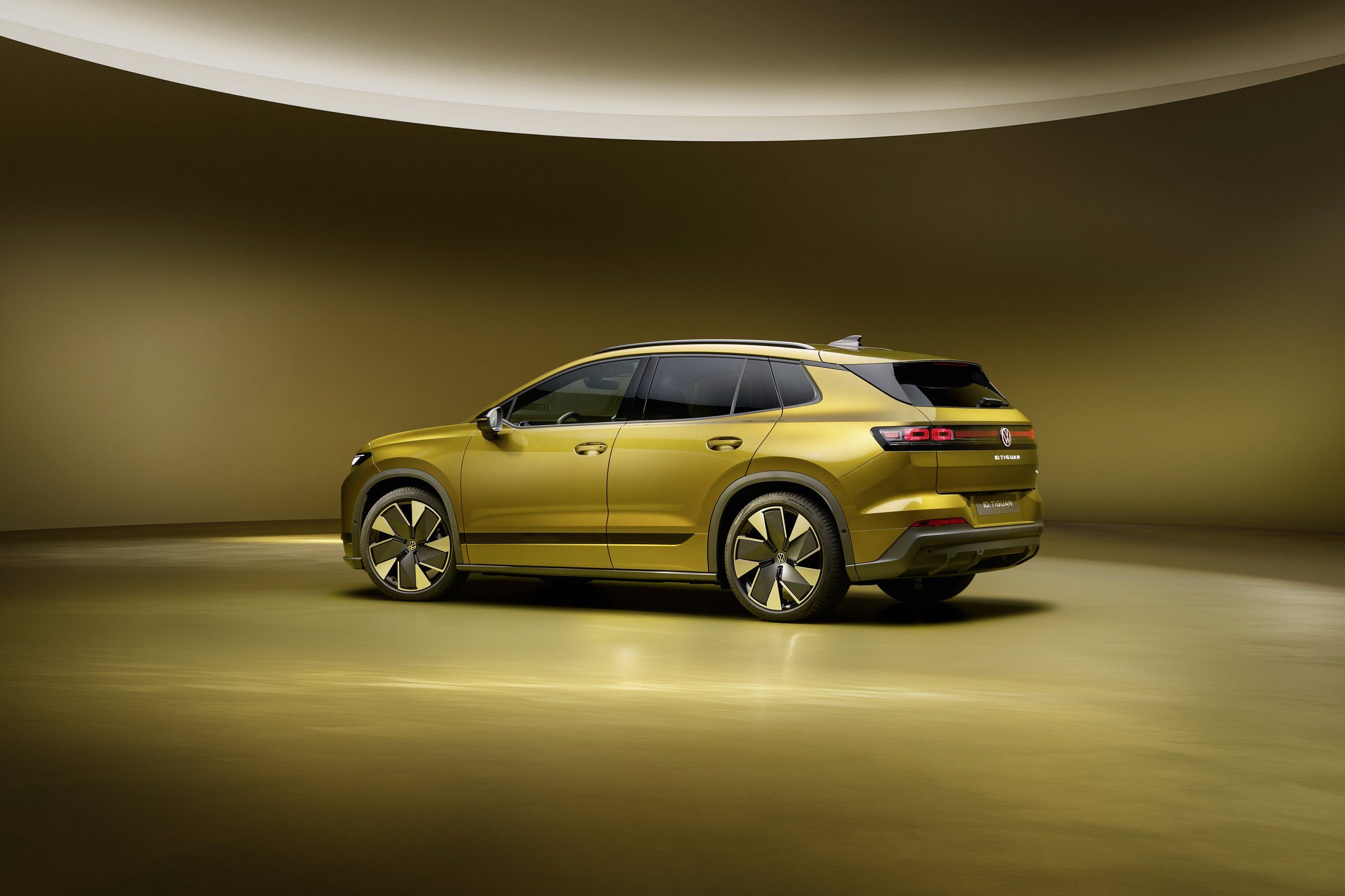 Volkswagen ID. Tiguan in Olive Bronze metallic, rear three-quarter view showing the full-width light bar