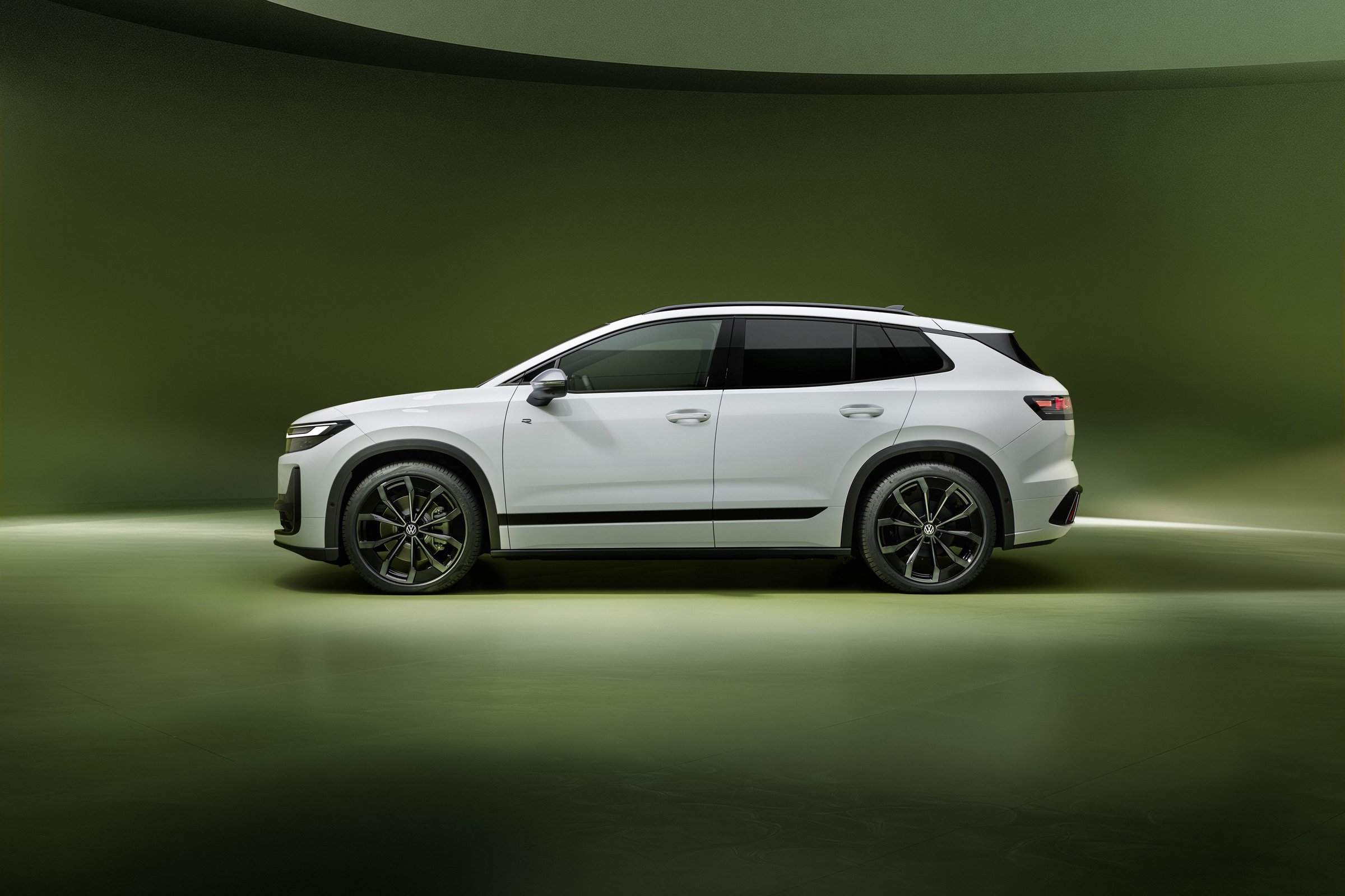 White Volkswagen ID. Tiguan, side profile against a green studio backdrop