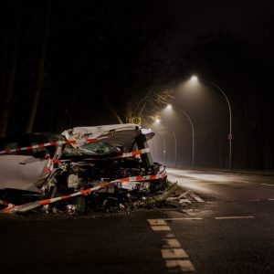 Wrecked white car taped off on a foggy street at night