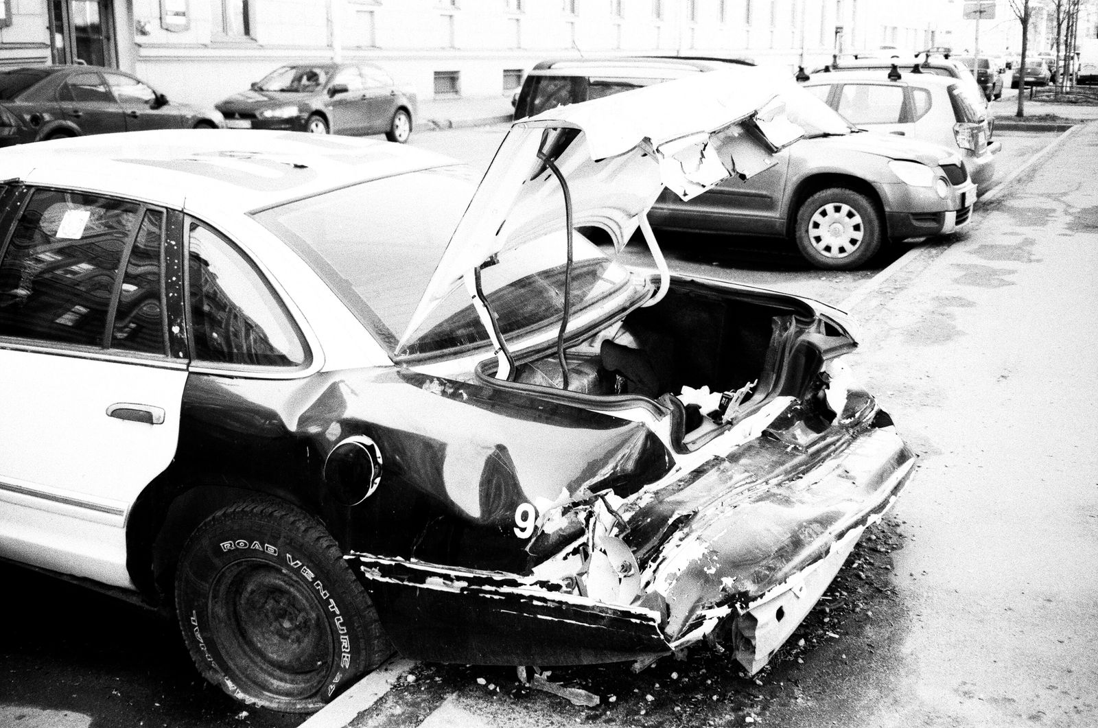 Injury Compensation After a Collision Calls for Detailed Proof 1 Black and white photo of a wrecked car parked on a city street