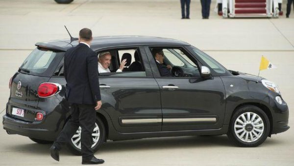 Pope Francis waves as a passenger in a Fiat 500L.